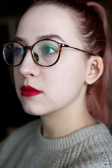 The pretty girl face in big glasses with vivid red lips  looks very upset