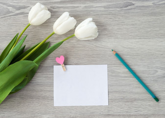 A sheet of paper with a red pen and flowers lies on a white wooden table. Leave a note on the table.