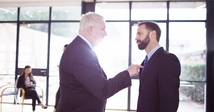 4K Mature businessman being aggressive & confrontational with younger colleague. Slow motion.