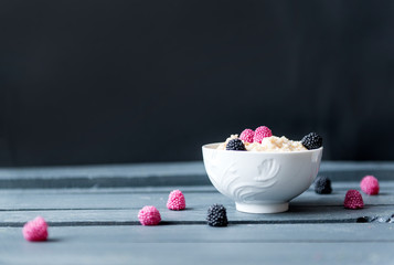 oatmeal with berries in a white plate on a dark background