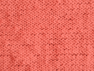 Texture of knitted woolen sweater dyed in Living Coral