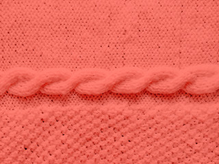 Texture of knitted woolen sweater dyed in Living Coral