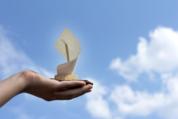 Sailing ship in hand against the blue sky with clouds. dream of traveling
