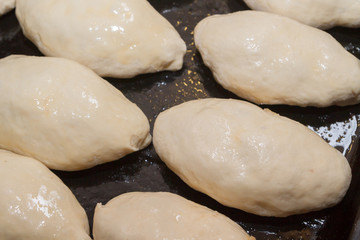 Freshly made pies lie on a baking sheet before cooking