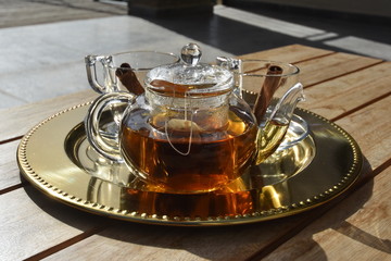 pot of fresh tea on tray with cinnamon sticks