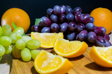 Orange slices and grapes on a wooden Board. Beautiful background of a set of fruits.