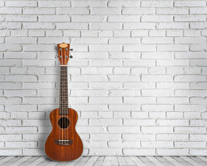 Fototapeta na wymiar Ukulele guitar on a white wall background. Concept of travel and lifestyle.