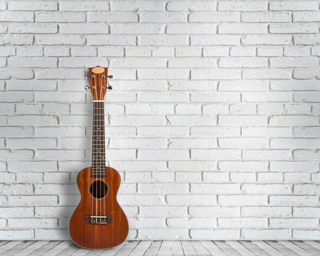 Ukulele guitar on a white wall background. Concept of travel and lifestyle. © YB