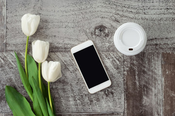 White  phone, coffee and flowers are on the table. Work at home. Freelance.
