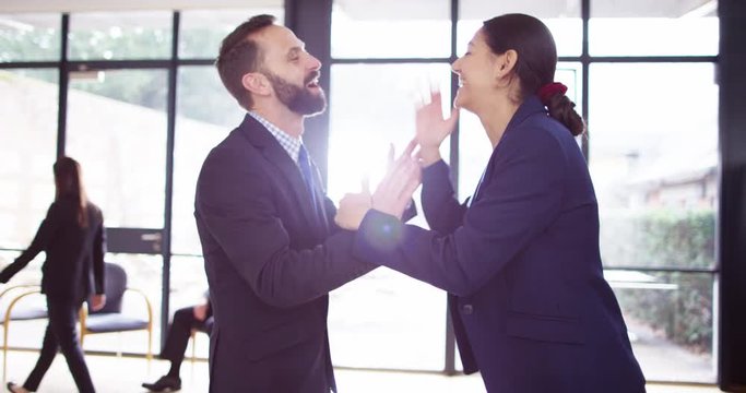 4K Socially awkward businessman attempts a high-five with female colleague but misses. Slow motion.