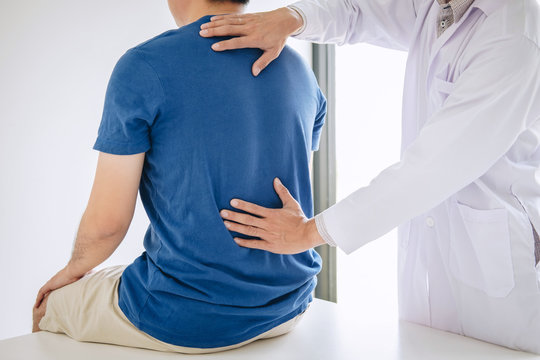 Doctor physiotherapist treating lower back pain patient after while giving exercising treatment on stretching in the clinic, Rehabilitation physiotherapy concept