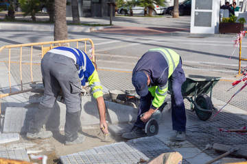 Roadworks. Two men paving brick pathway.