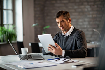 Male entrepreneur using digital tablet while working in the office.