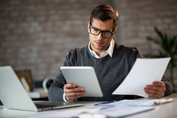 Businessman using touchpad while working on reports in the office.