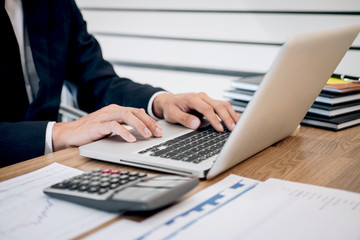 Businessman working new project on laptop computer with report document and analyze, calculating financial data on graph documents, doing finance making notes statistics