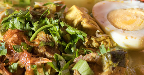 Soto Ayam is a chicken soup served with vegetables and rice - Image