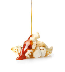 Liquid caramel pouring on popcorn against white background
