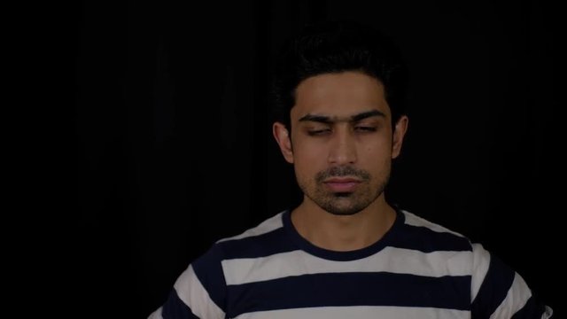 Young Indian man tired and exhausted looks directly at the camera with disappointment and doesn't change his facial expression 