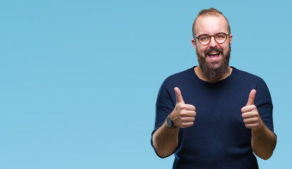 Fototapeta premium Young caucasian hipster man wearing sunglasses over isolated background approving doing positive gesture with hand, thumbs up smiling and happy for success. Looking at the camera, winner gesture.