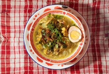Soto Ayam is a chicken soup served with vegetables and rice - Image