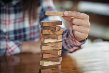hand of businessman pulling out or placing wood block on the tower. plan and strategy in business. ...