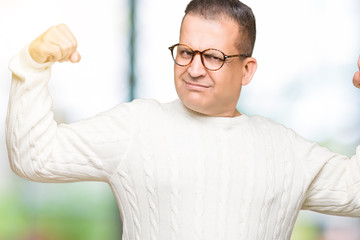 Naklejka premium Middle age arab man wearing glasses over isolated background showing arms muscles smiling proud. Fitness concept.