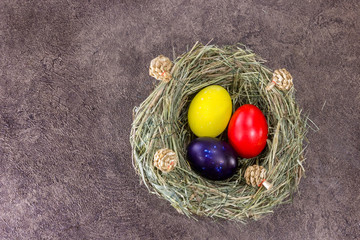 Handmade colorfull Easter eggs in selfmade grass nest on dark background