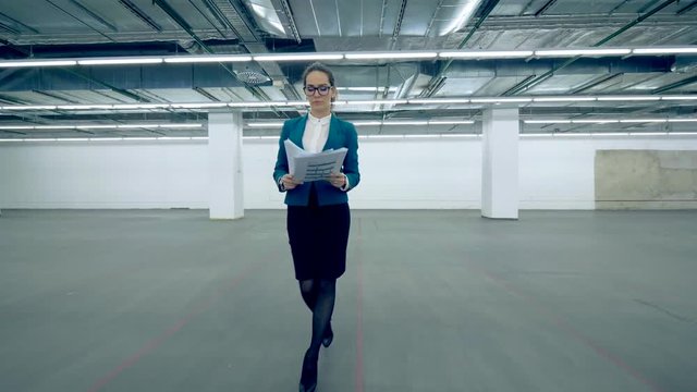 A woman throws away papers and starts to dance in an office room.