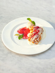 Apple strudel table raisins ice cream mint sultana berries sauce red green white plate close up top view