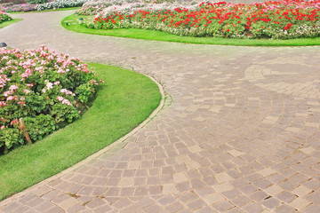 Stone pathways in nature garden with colorful ornamental flowers background