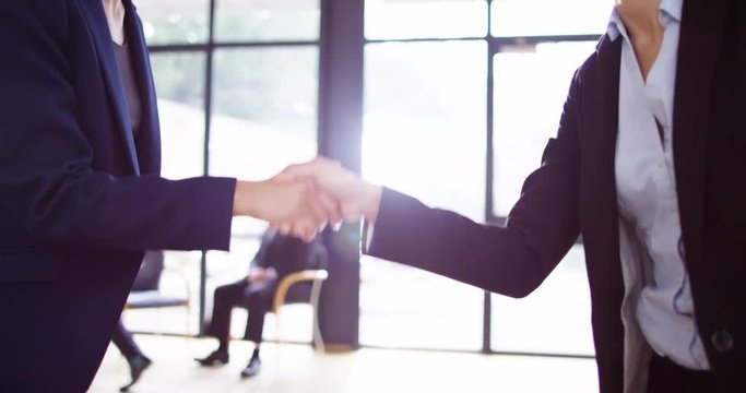 4K Business to business sales concept, female executives greeting with a handshake in office lobby. Slow motion.