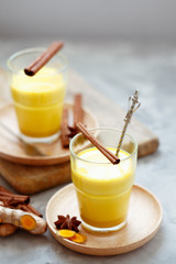 Golden tea with almond milk, turmeric, cinnamon, honey and ginger. Healthy detox morning beverage with spices on light backround close up