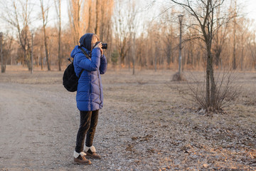 Fototapeta premium A woman photographer holds a camera in her hands. The concept of a woman photojournalist.