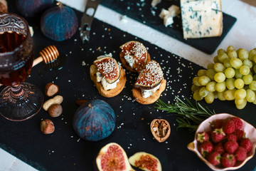 Figs. Sandwiches with figs, cheese, honey and nuts on a shale board. Brochette with cheese and figs. Homemade. Everyday autumn kitchen