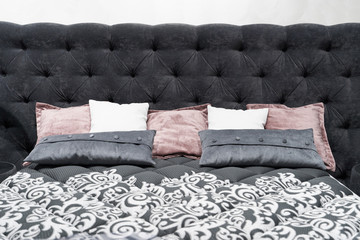 Bed with a large gray soft headboard and pillows. Close-up