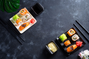 Various Fresh and delicious sushi set on black slate with slate sticks, sauce and nori on black stone background , flat lay
