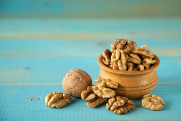 Walnuts on blue rustic table in wooden bowl