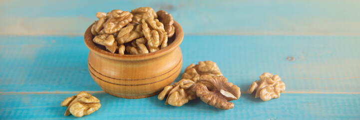 Walnuts on blue rustic table in wooden bowl