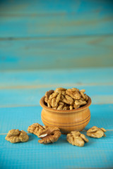Walnuts on blue rustic table in wooden bowl