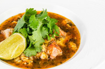 Crab with chili sauce, lime, parsley and rice on a plate on a white background