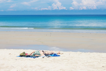 Fototapeta na wymiar Beautiful caucasian woman sunbathing on the beach.Young woman resting on sand at tropical beach.