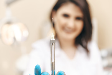 Closeup photo of female dentist in the dental room holding oral syringe
