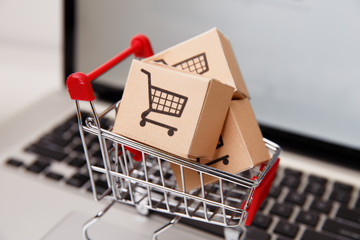 paper boxes in a shopping cart on a laptop keyboard. Concepts about online shopping that consumers...