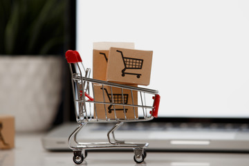 paper boxes in a shopping cart on a laptop keyboard. Concepts about online shopping that consumers...