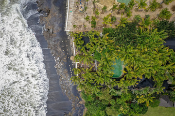 Aerial view of beach with black sand and beach club with swimming pool, Canggu, Bali, Indonesia