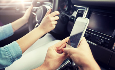 road trip, travel, destination technology and people concept - happy man and woman with navigator on smartphone driving in car