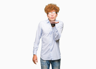 Young handsome business man with afro wearing glasses looking at the camera blowing a kiss with hand on air being lovely and sexy. Love expression.