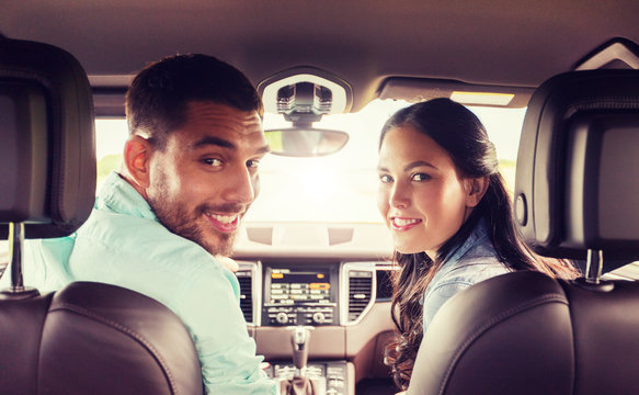 Leisure, Road Trip, Travel And People Concept - Happy Man And Woman Driving In Car And Looking Back