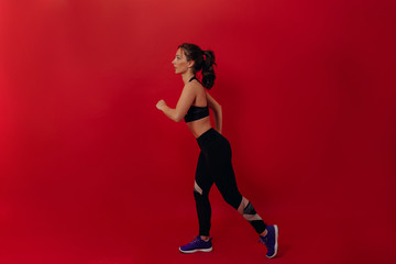 Fototapeta na wymiar Full length photo of sporty confident modern woman running over red background. Hispanic female in the sport