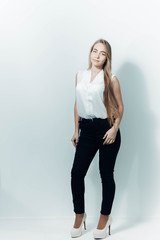 portrait of a beautiful long-haired blonde girl with blue eyes in business clothes in a white studio.